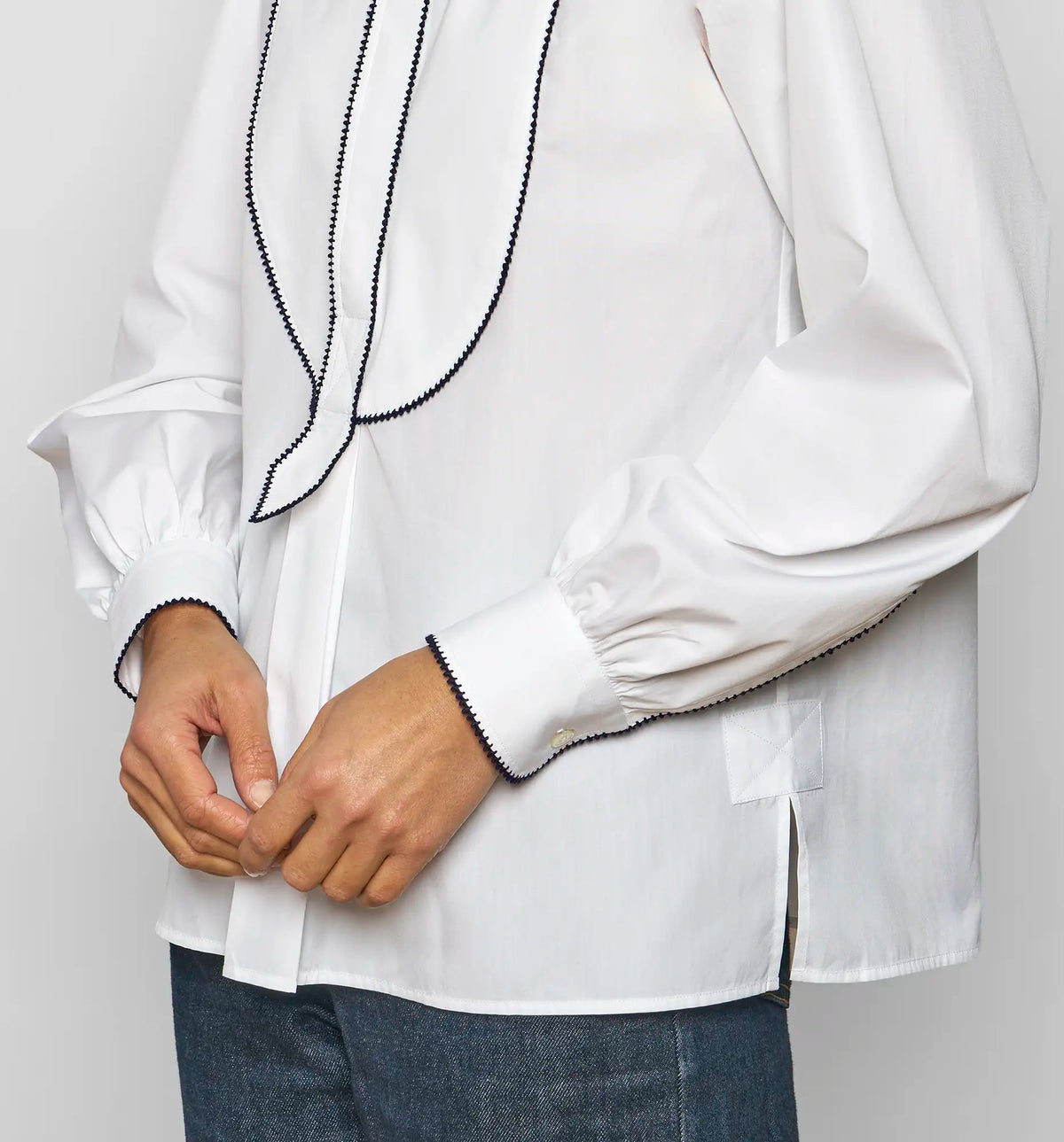 Detail of navy embroidered stitch on the front bib of a white cotton poplin shirt by Sébline.