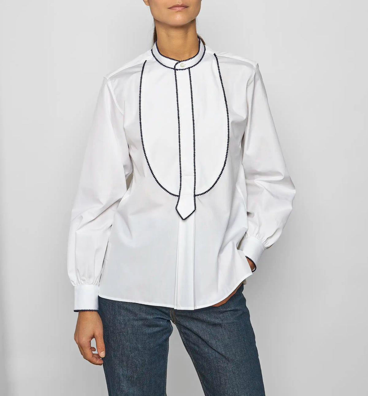Model wearing a white cotton poplin embroidered bib pullover shirt by Sébline, front view.