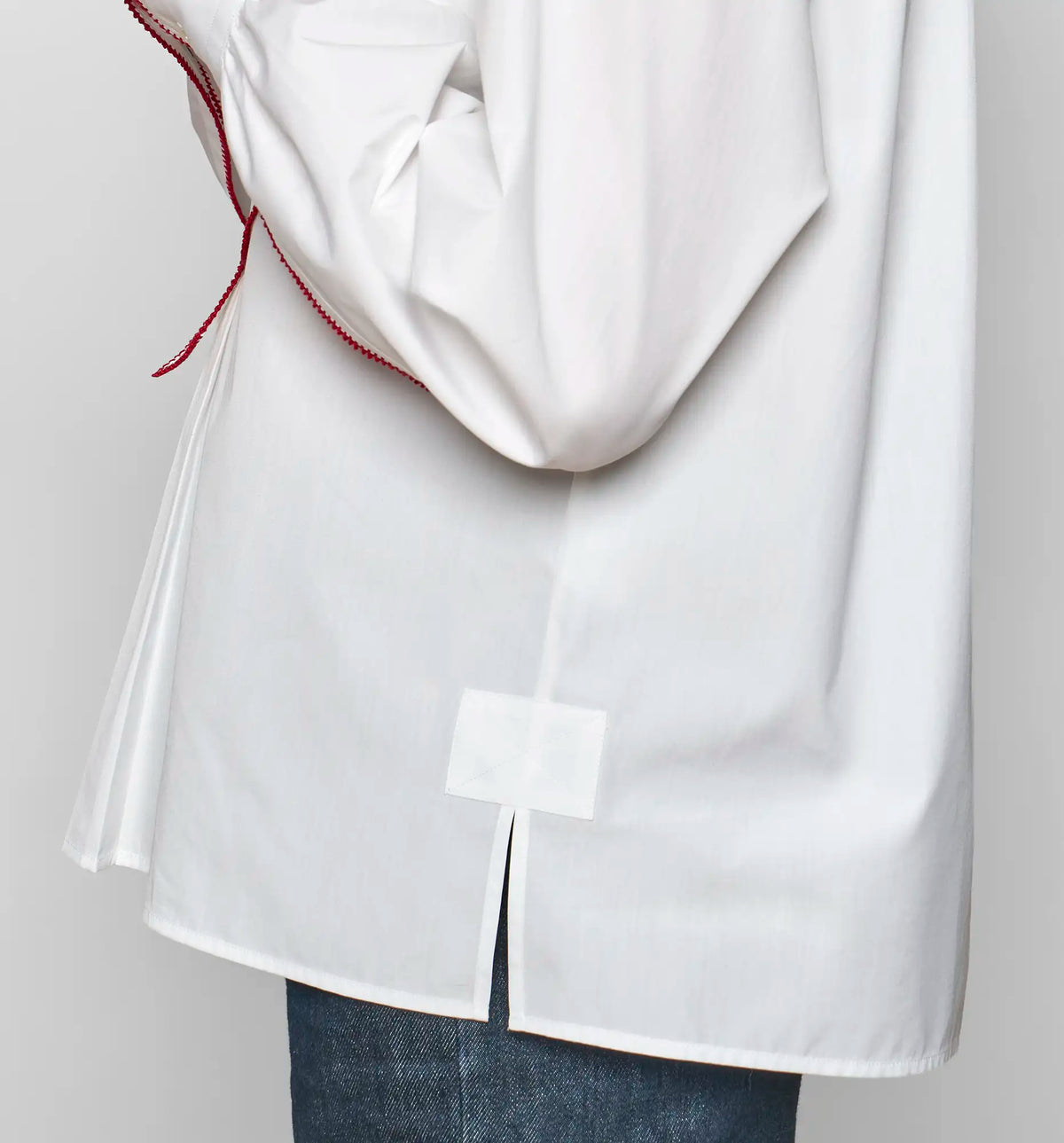 Detail of the back hem vent with a square reinforcement patch on a white cotton poplin shirt by Sébline.