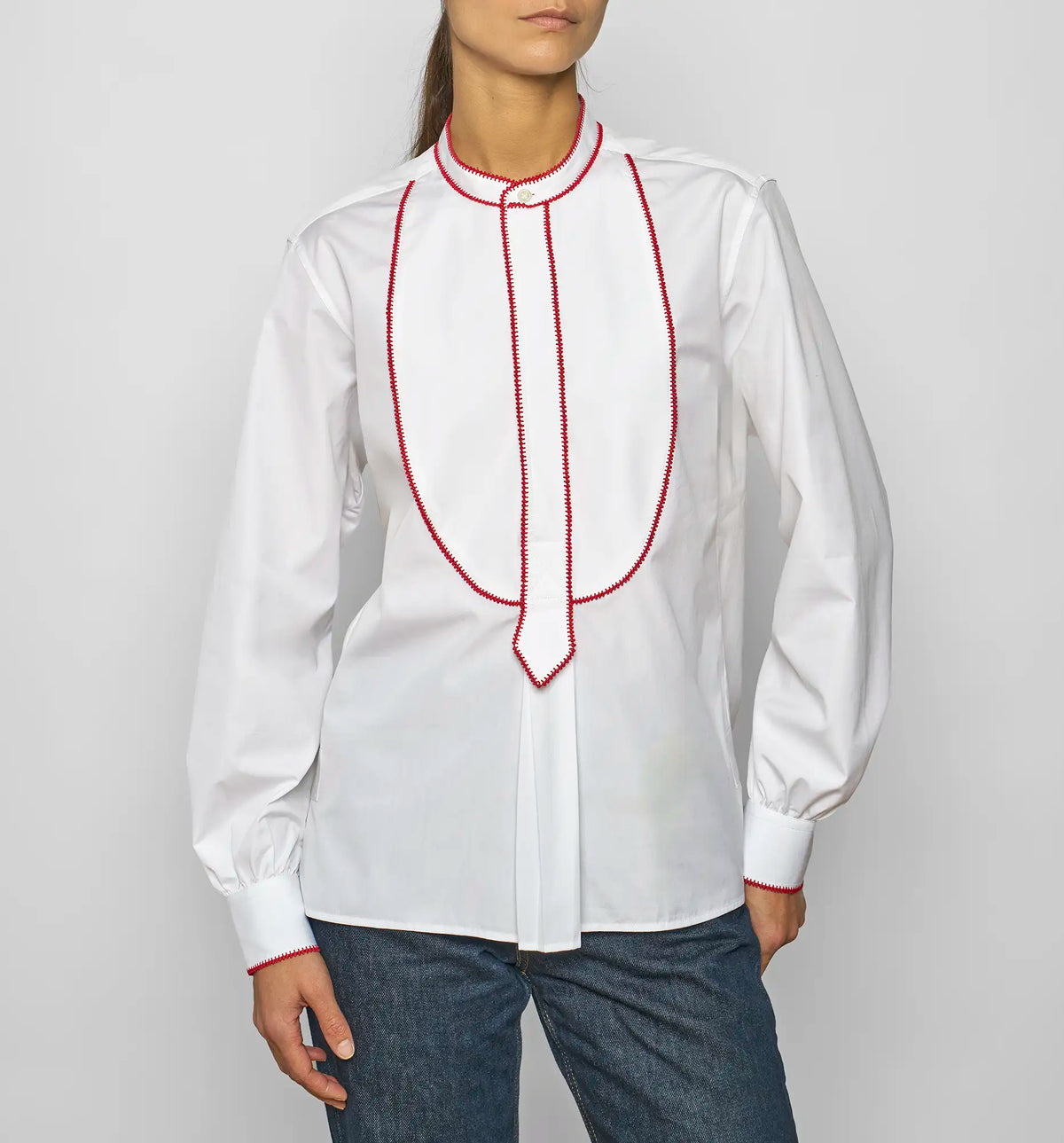 Model wearing a white cotton poplin pullover shirt with red embroidered bib by Sébline, front view.