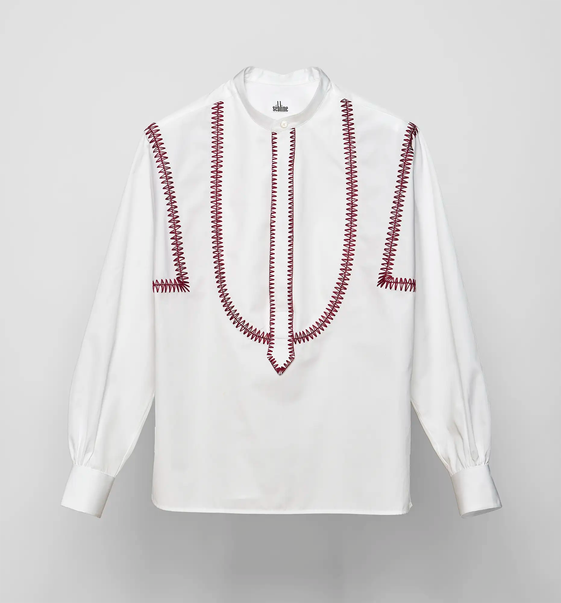 White Sébline pullover shirt with bordeaux embroidery on the front bib and shoulders, long sleeves, band collar.