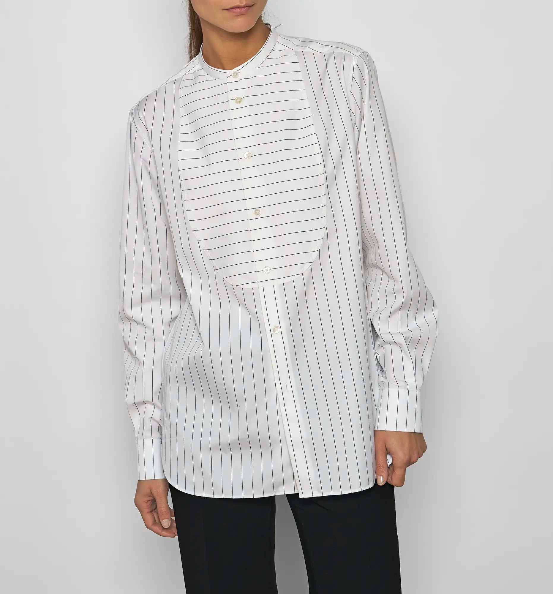 Model wearing a Sébline white long-sleeve pinstripe shirt with a striped bib, front view with the shirt tucked in.