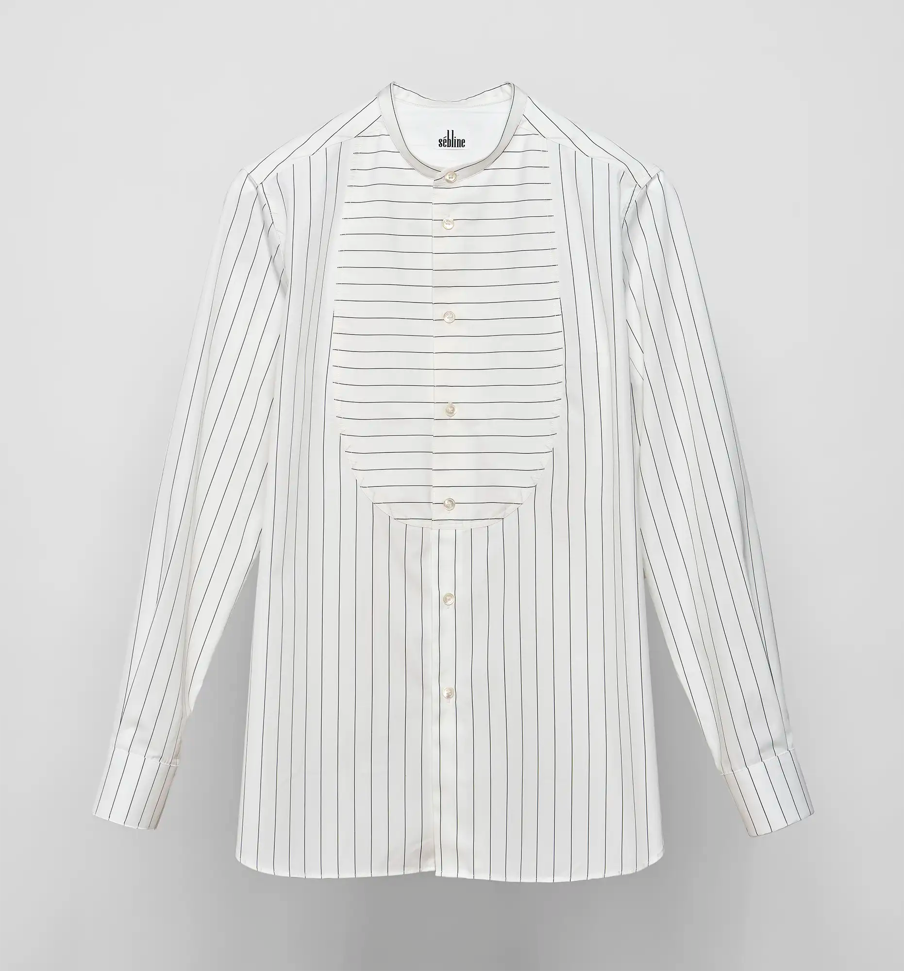 Sébline long-sleeve white shirt with black pinstripes and a horizontally striped bib, front flat lay on grey background.