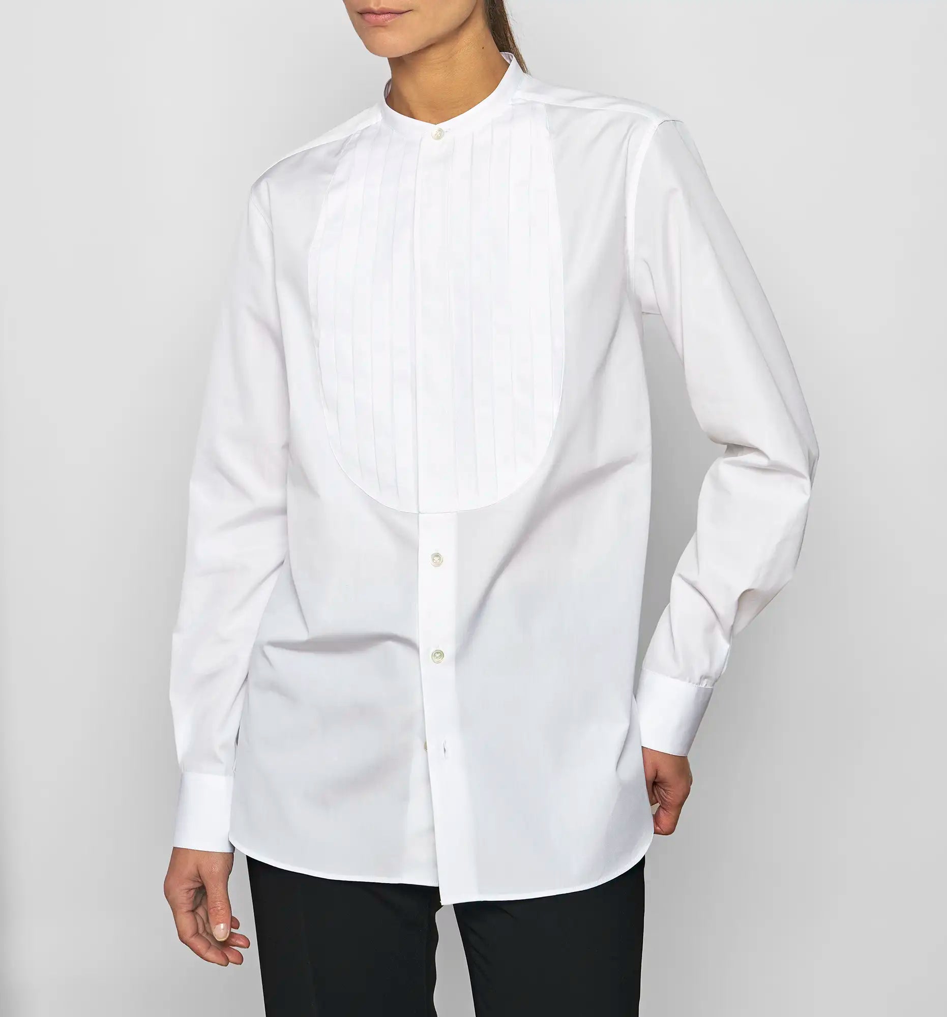 Model wearing a Sébline white long-sleeve shirt, front view with the shirt hem visible over trousers.