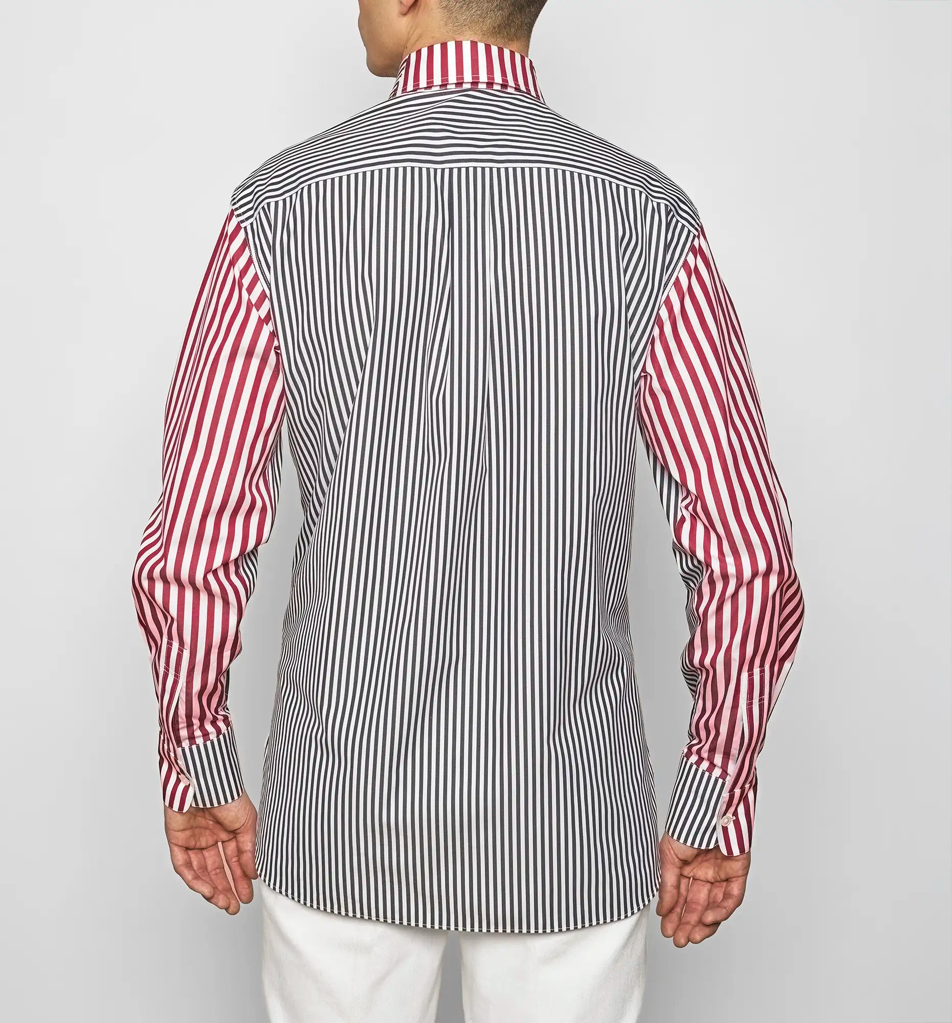 Person wearing a red and white striped shirt with a black and white striped vest on a plain background