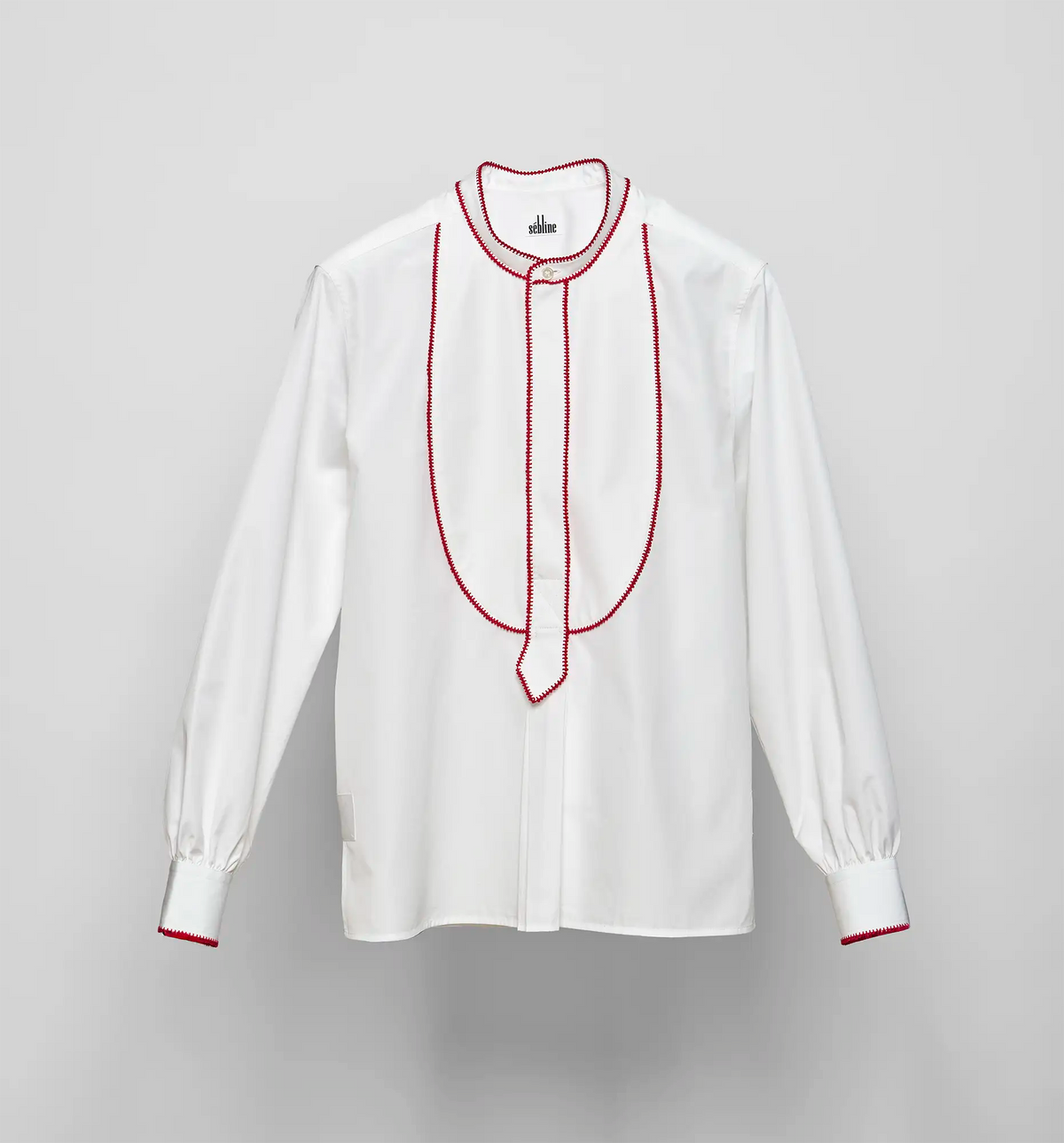 White cotton poplin pullover shirt with red embroidered bib detail by Sébline, front view on neutral background.