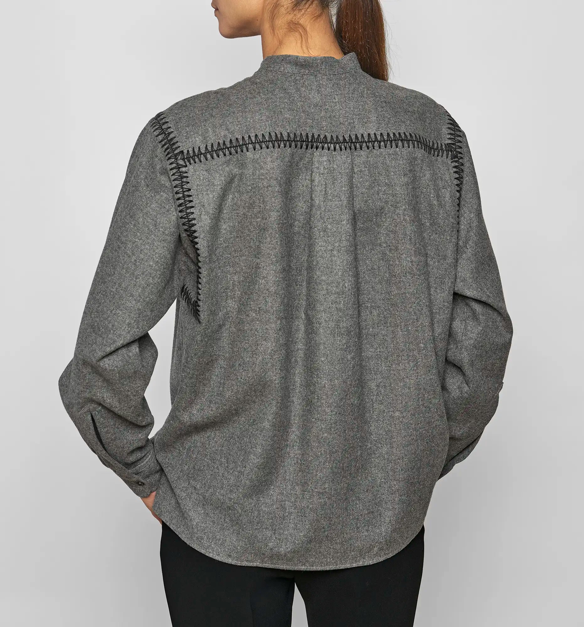 Back view of a model wearing a charcoal Sébline pullover shirt with black embroidered detailing.