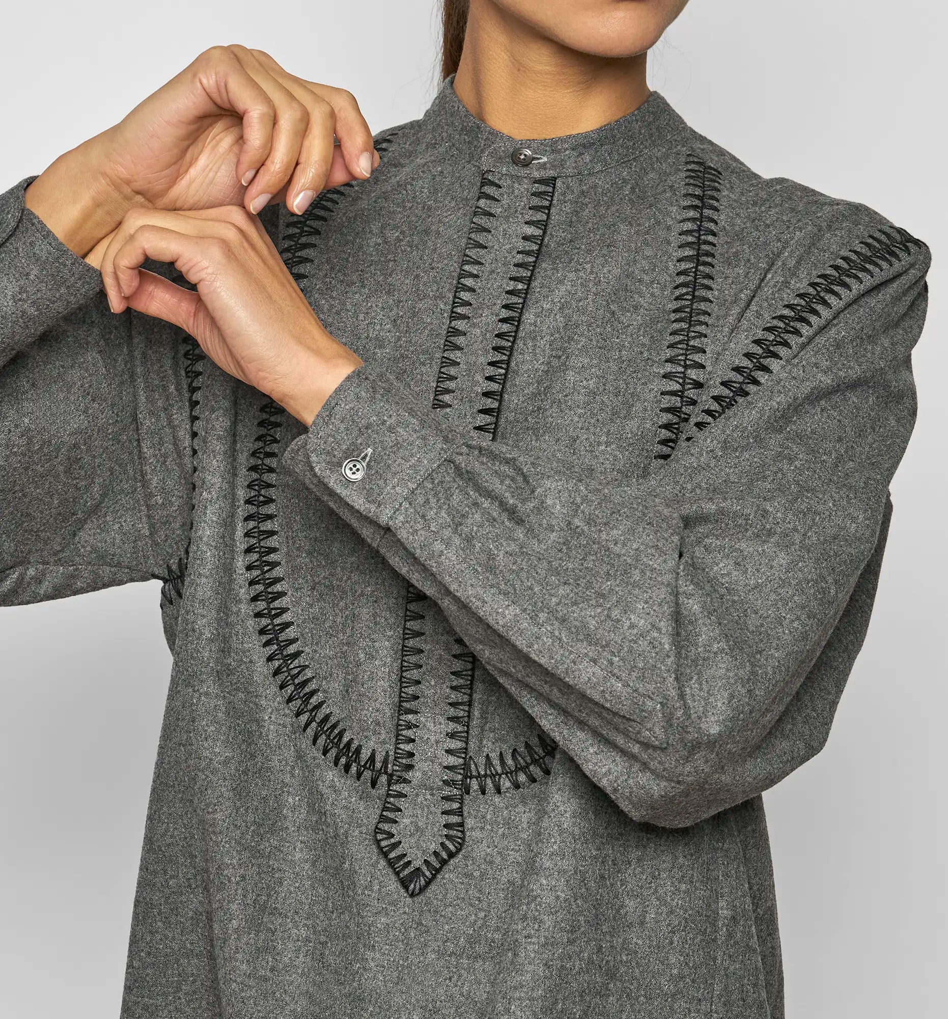 Close-up of the front embroidered detailing on a charcoal Sébline pullover shirt worn by a model.