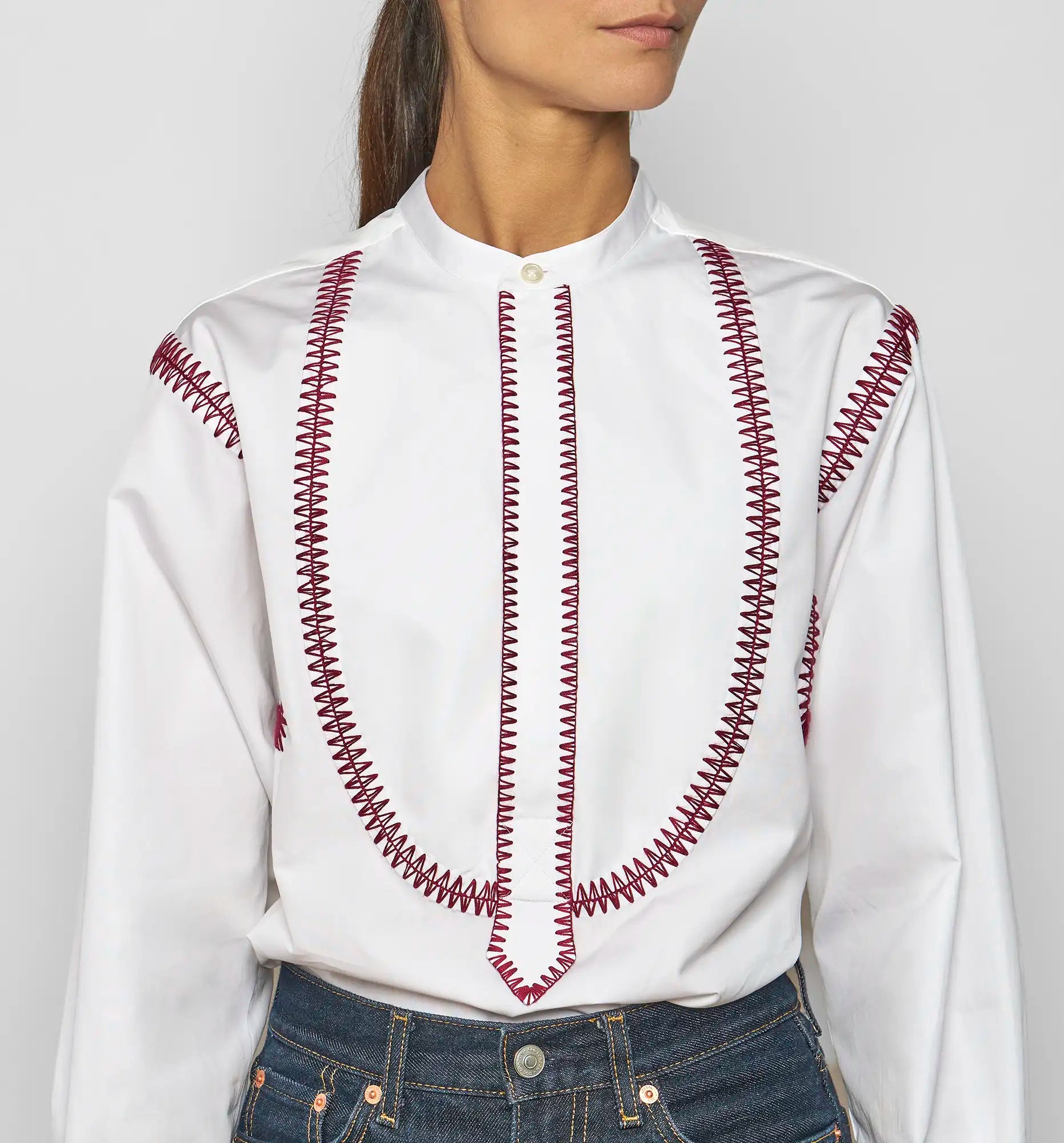 Model wearing a white Sébline pullover shirt with bordeaux embroidered bib, front view.