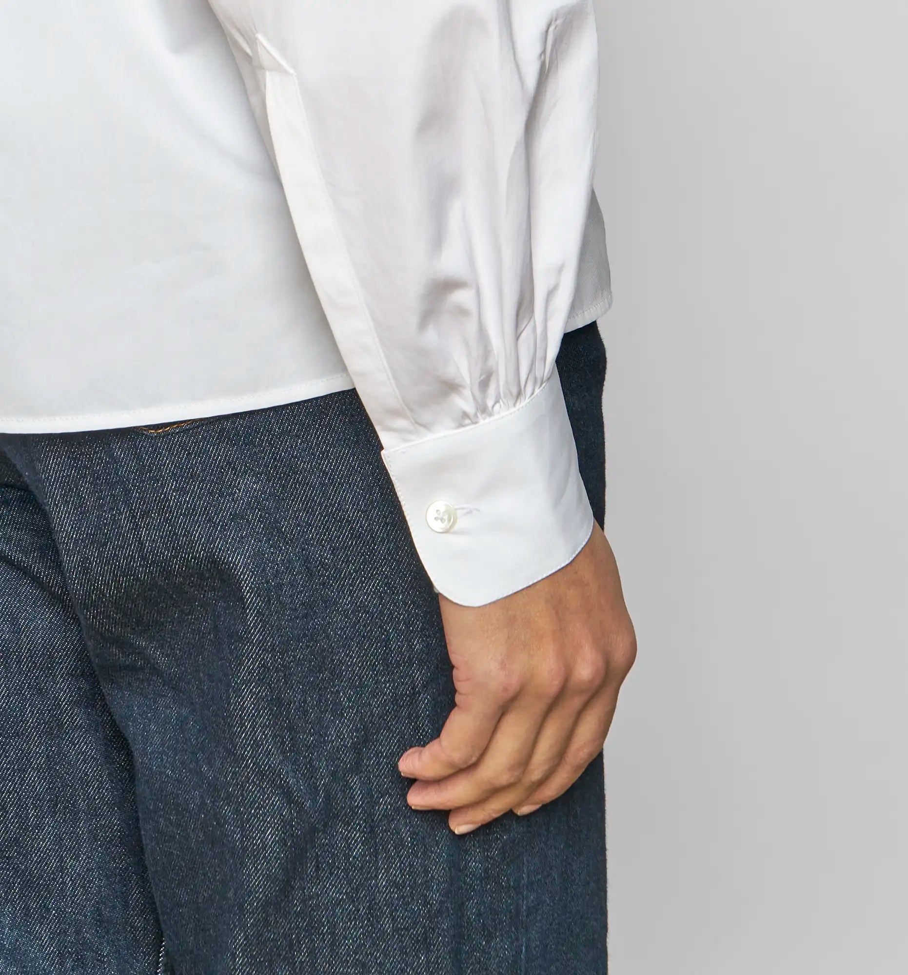 Close-up of sleeve and cuff of a white Sébline pullover shirt with bordeaux embroidery.