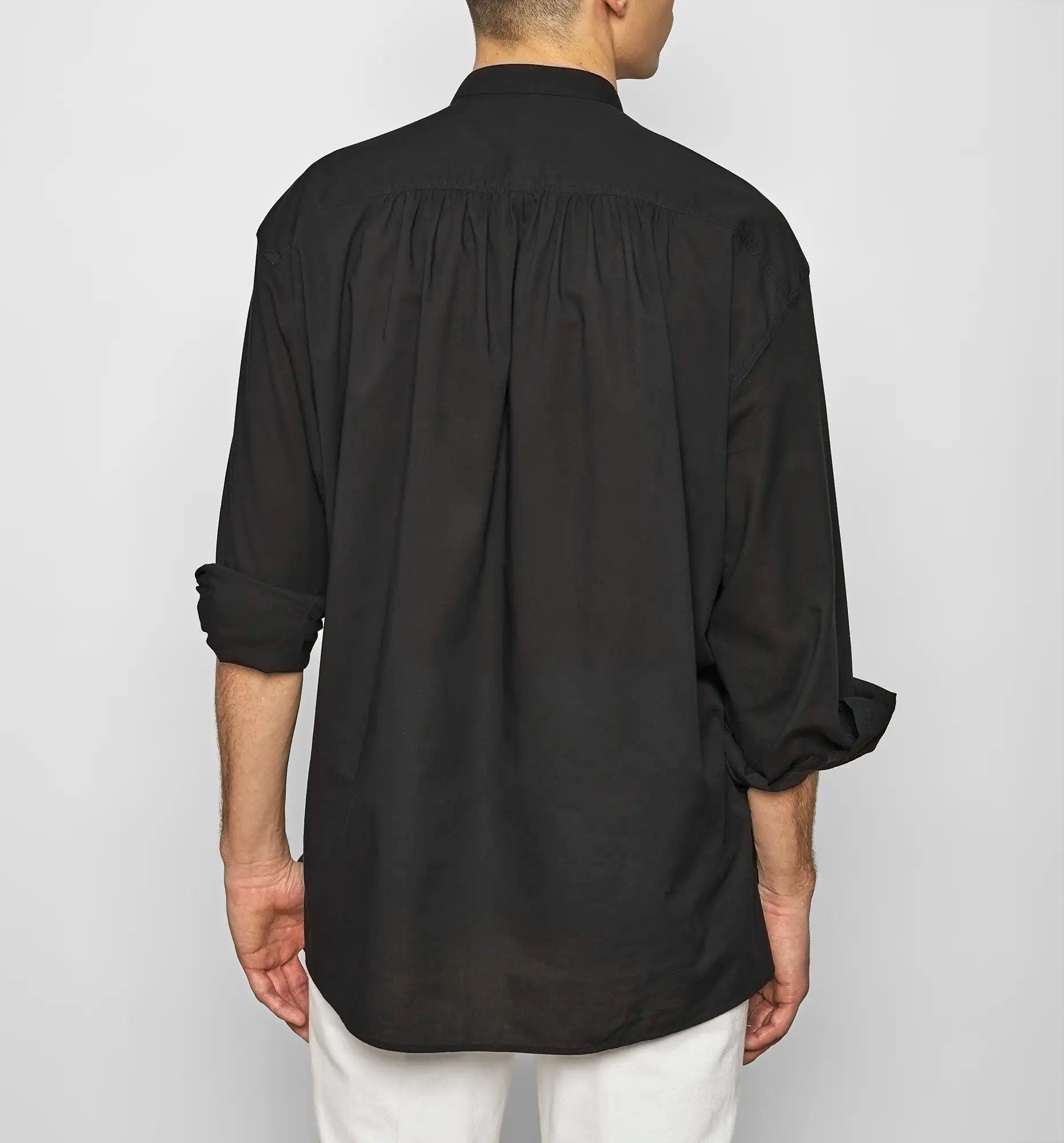 Back view of a black Sébline pullover shirt worn untucked by a model