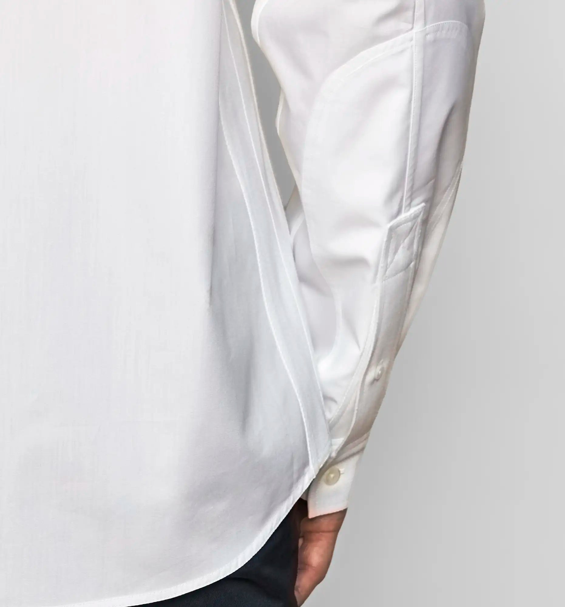 Detail view of the side seam and the cuff of a white Sébline shirt worn by a model