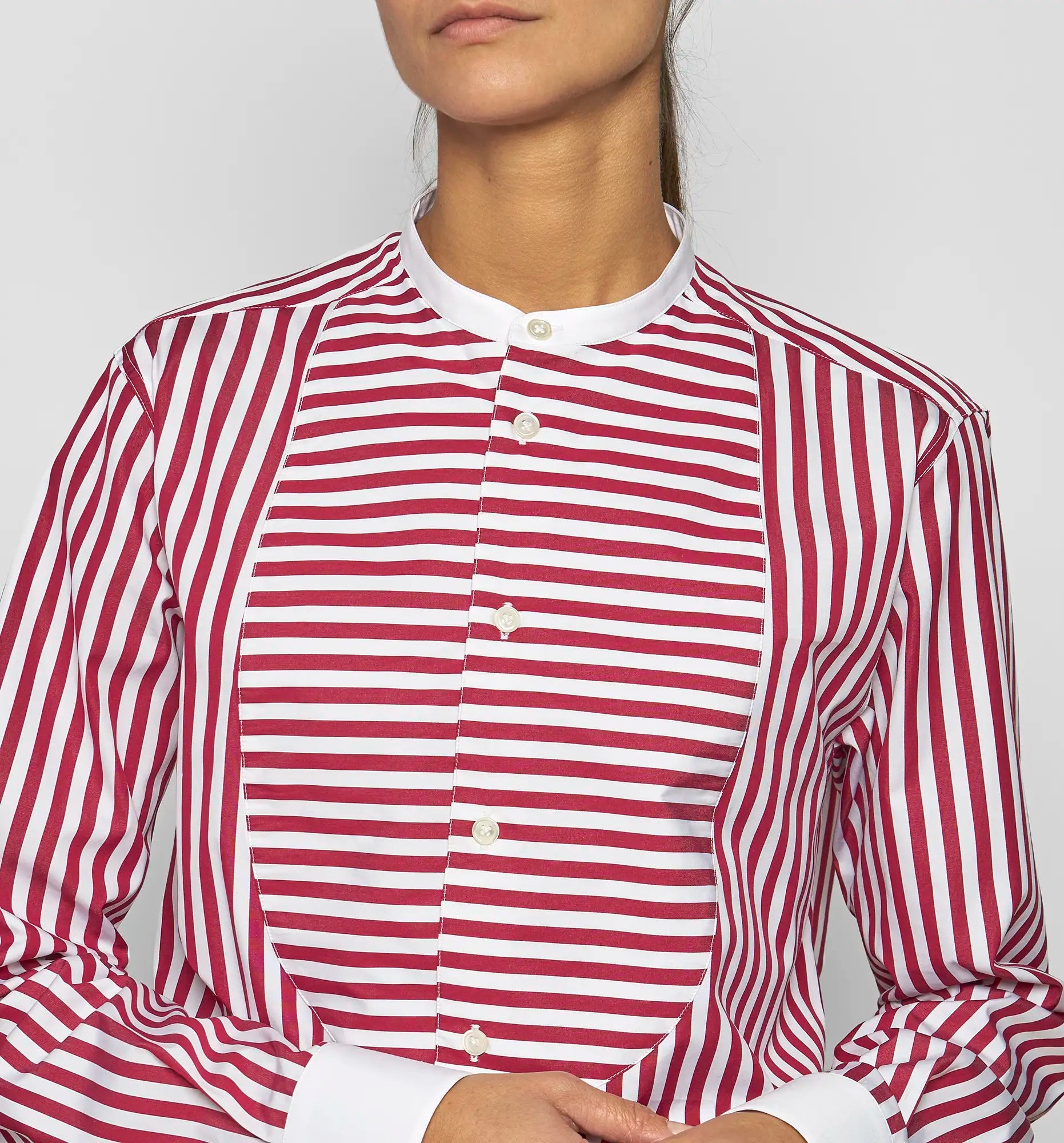 Close-up of a model wearing a Sébline red-and-white striped shirt showing the bib panel and band collar.